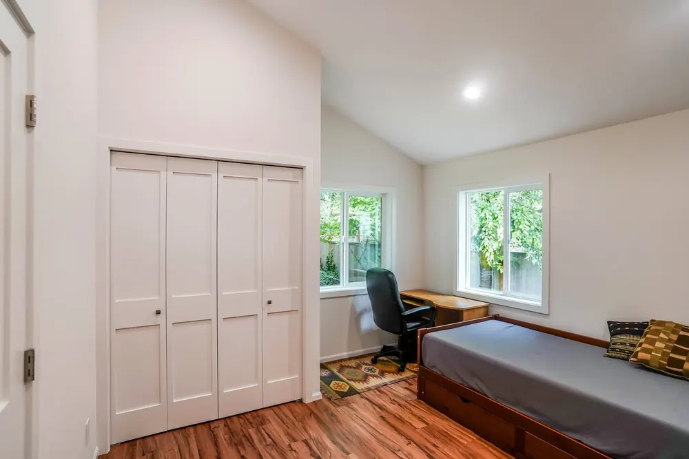Bedroom with closet doors and two windows