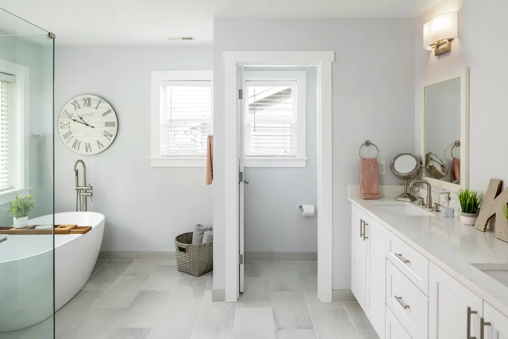 Bathroom with a freestanding tub, glass shower and wall clock