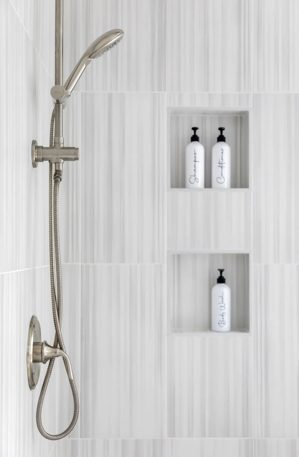 Shower niches and handheld shower on light tile