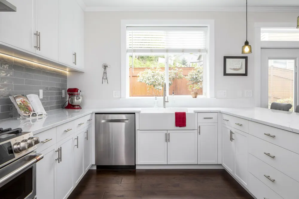 White kitchen with a gray subway backsplash and a window over the sink