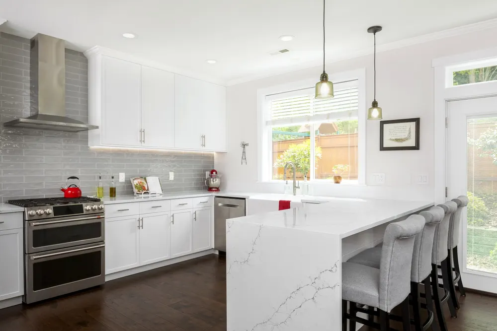 White kitchen with gray subway tile and peninsula seating