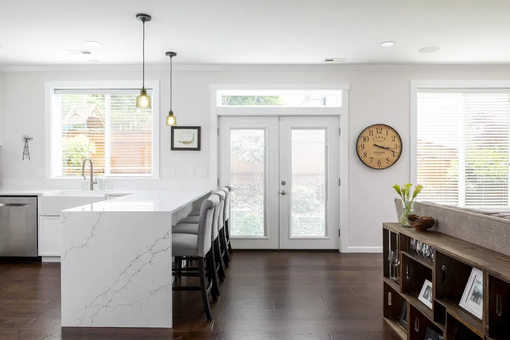 Waterfall island with pendant lights and French doors beyond