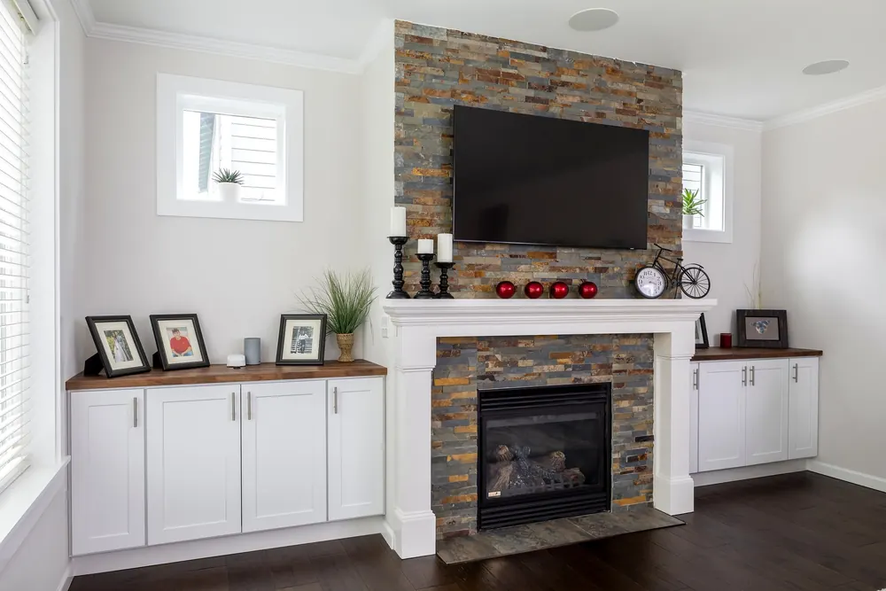 Stacked-stone fireplace with a mounted TV and white built-ins