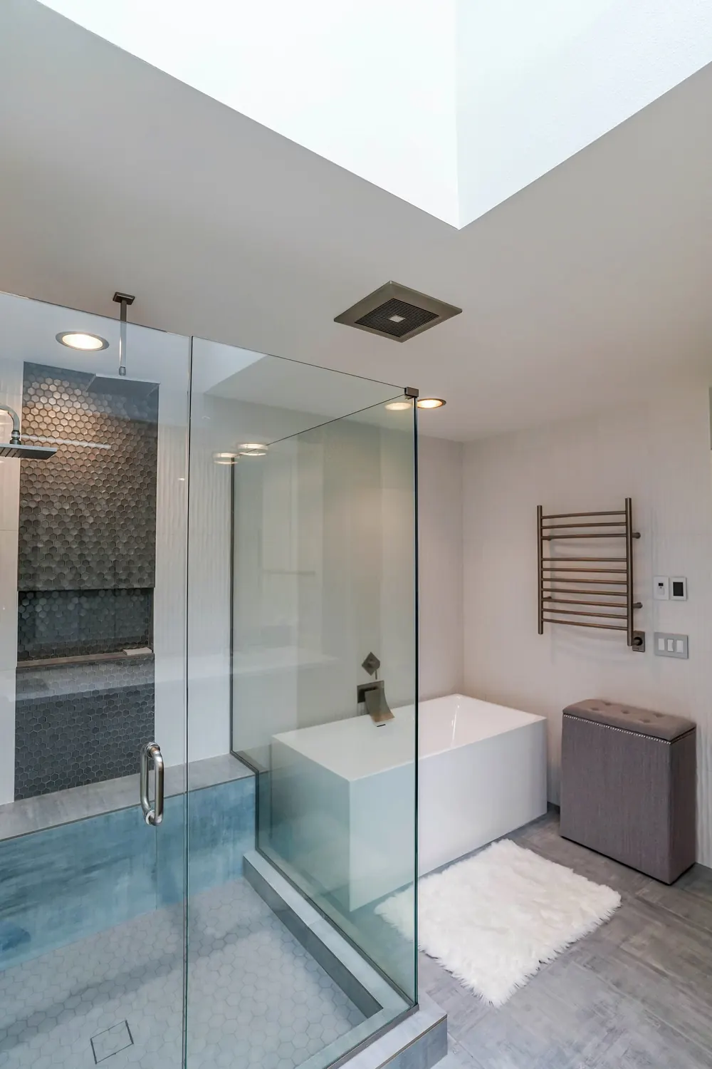 Glass shower beside the tub under a skylight