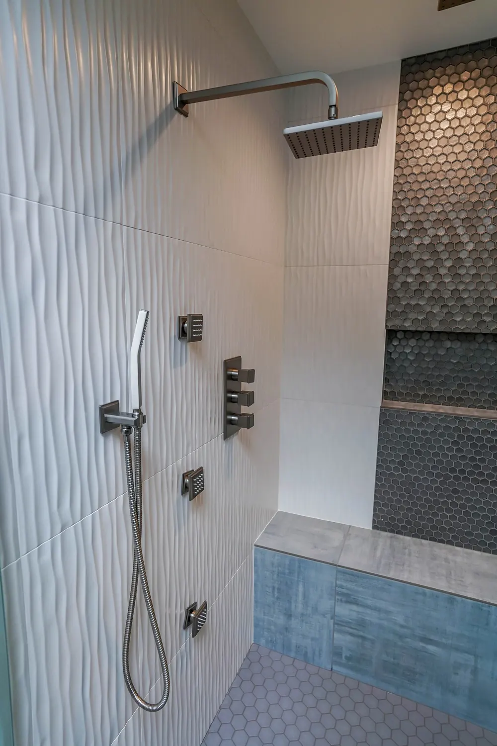 Walk-in shower with a rain head, handheld wand and dark mosaic stripe