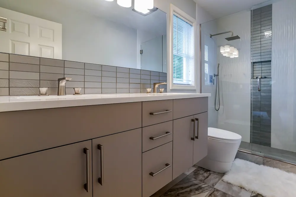 Long vanity with a gray tile backsplash and the tub at the far end
