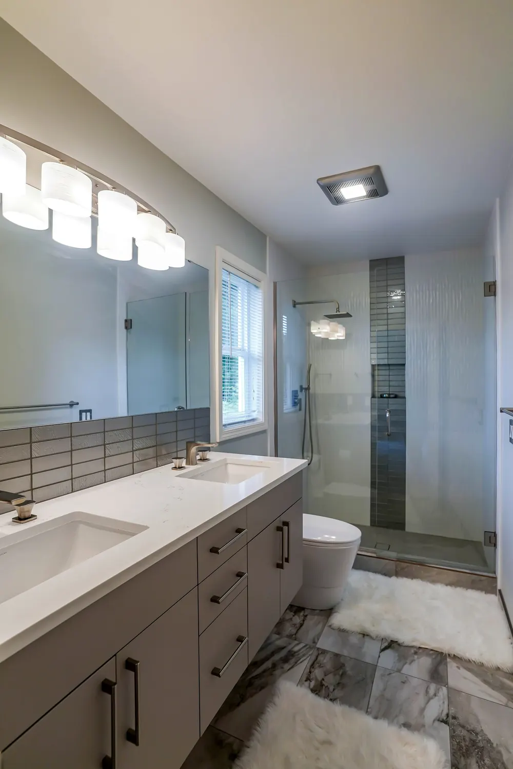 Vanity with wall lights and a view toward the shower