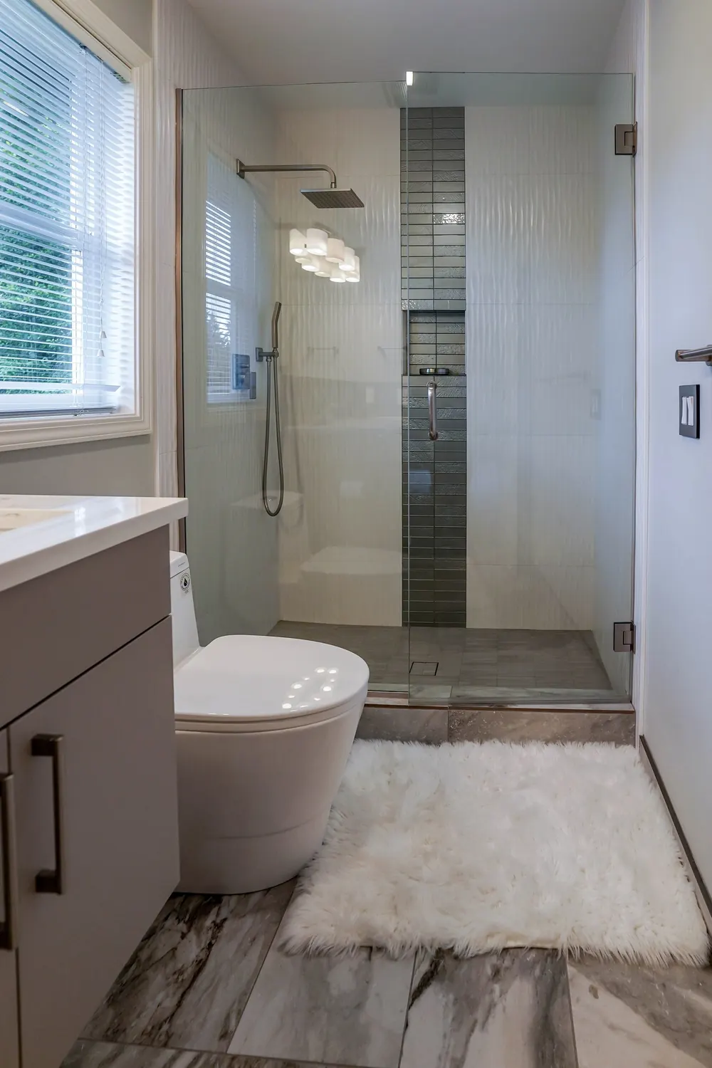 Shower with a dark mosaic stripe, toilet and vanity
