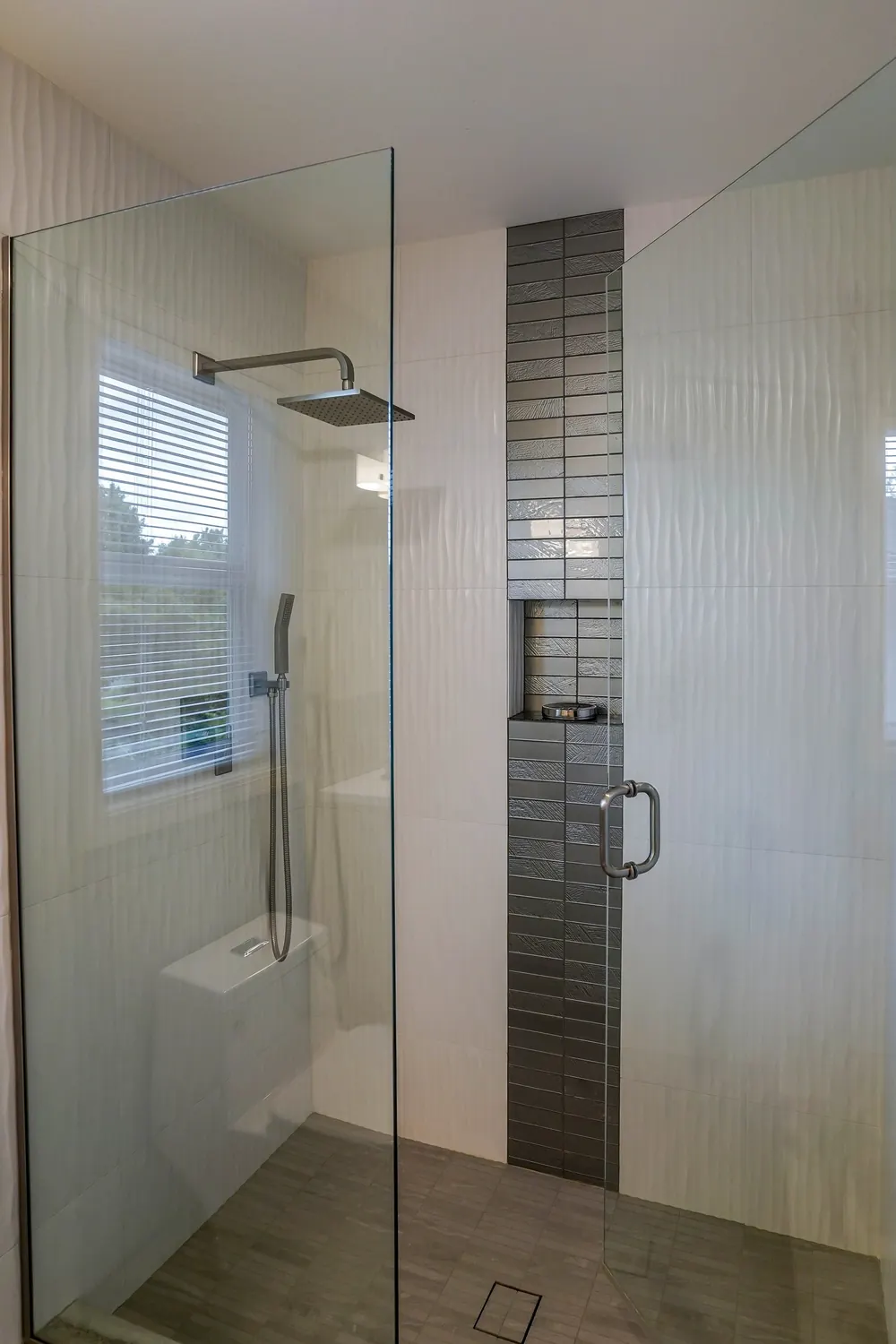 Glass shower with a vertical dark tile accent