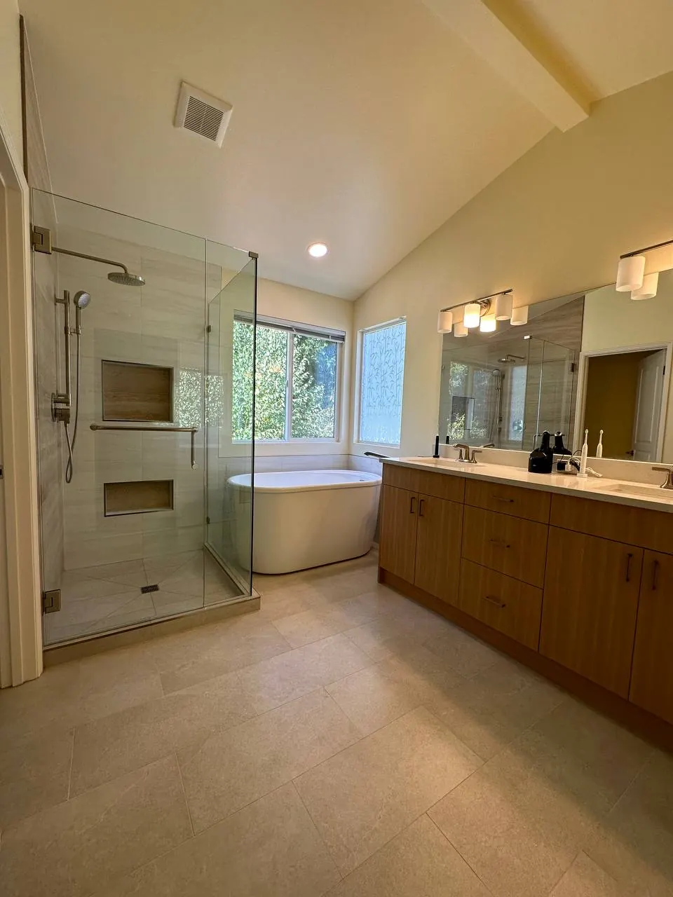 Primary bath with a glass shower, freestanding tub and wood double vanity