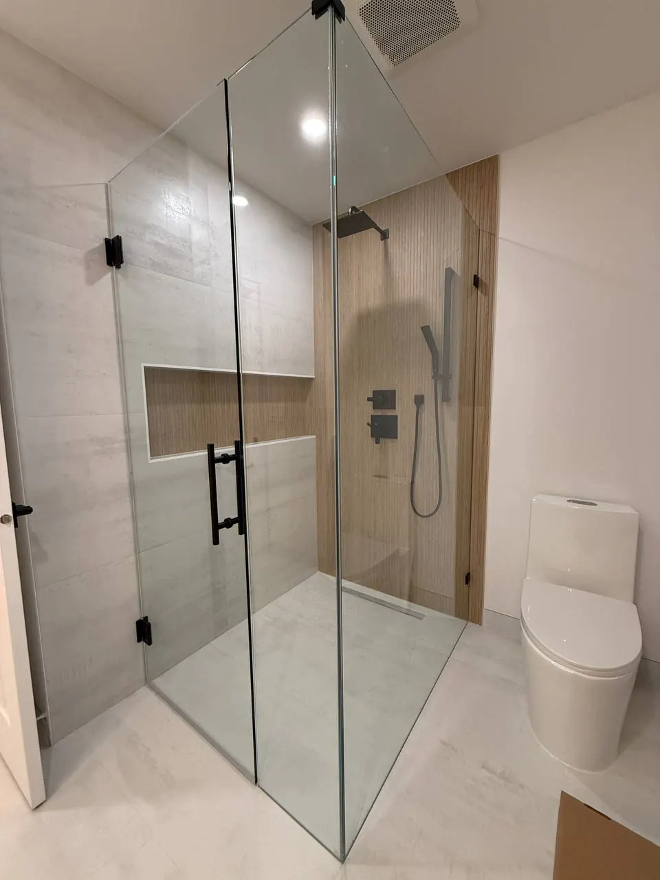 Frameless glass shower with a long niche and wood-look accent wall