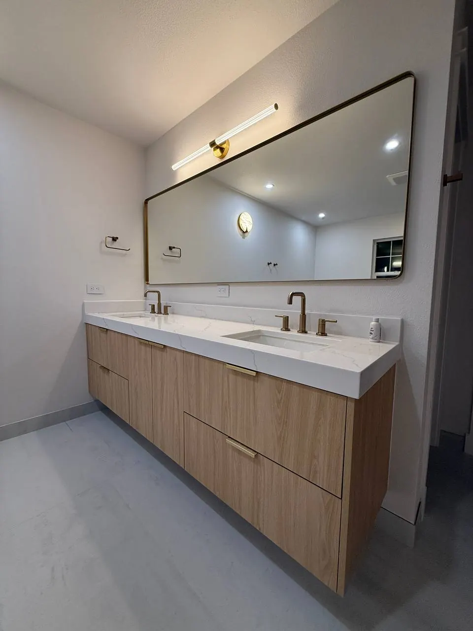 Long wood vanity with a wide black-framed mirror