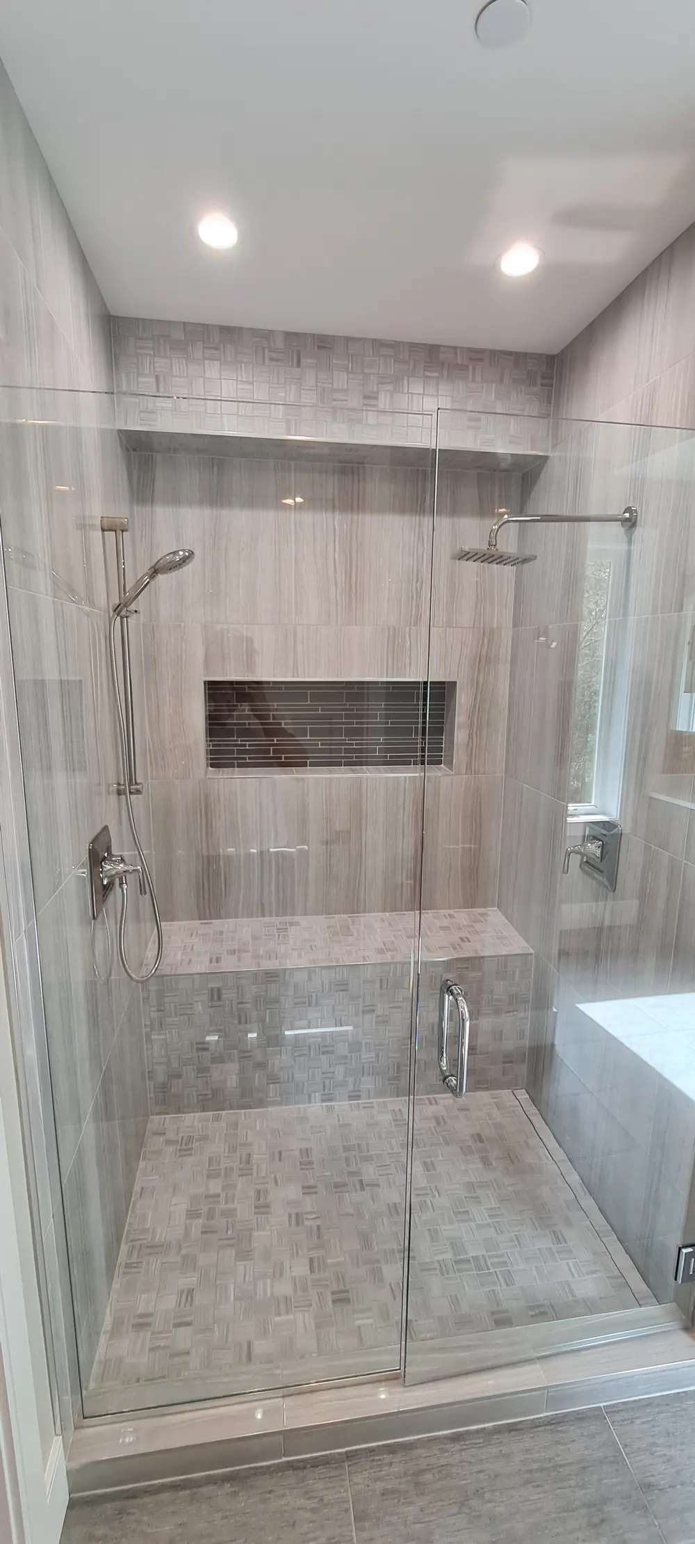 Walk-in shower with a glass enclosure, long niche and tiled bench
