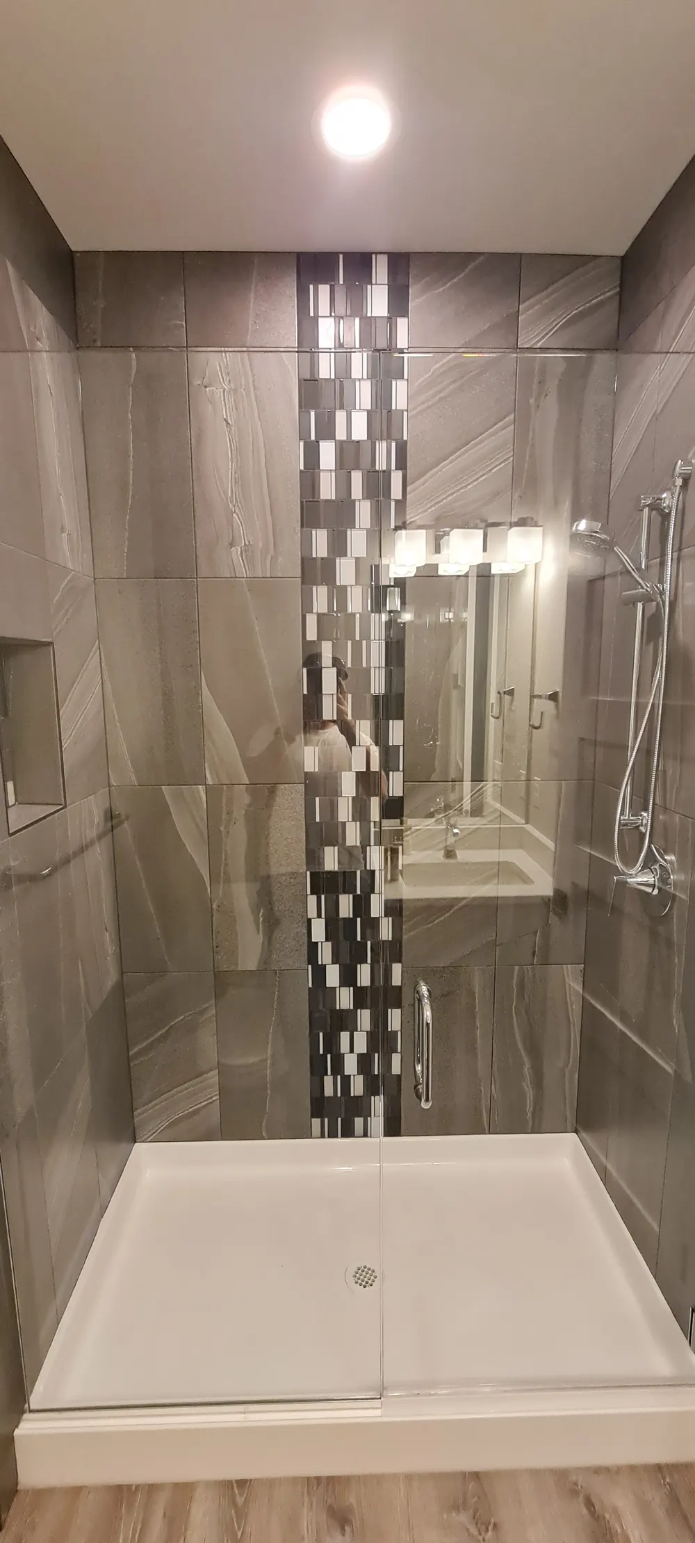 Shower with gray wood-look tile and a vertical mosaic stripe