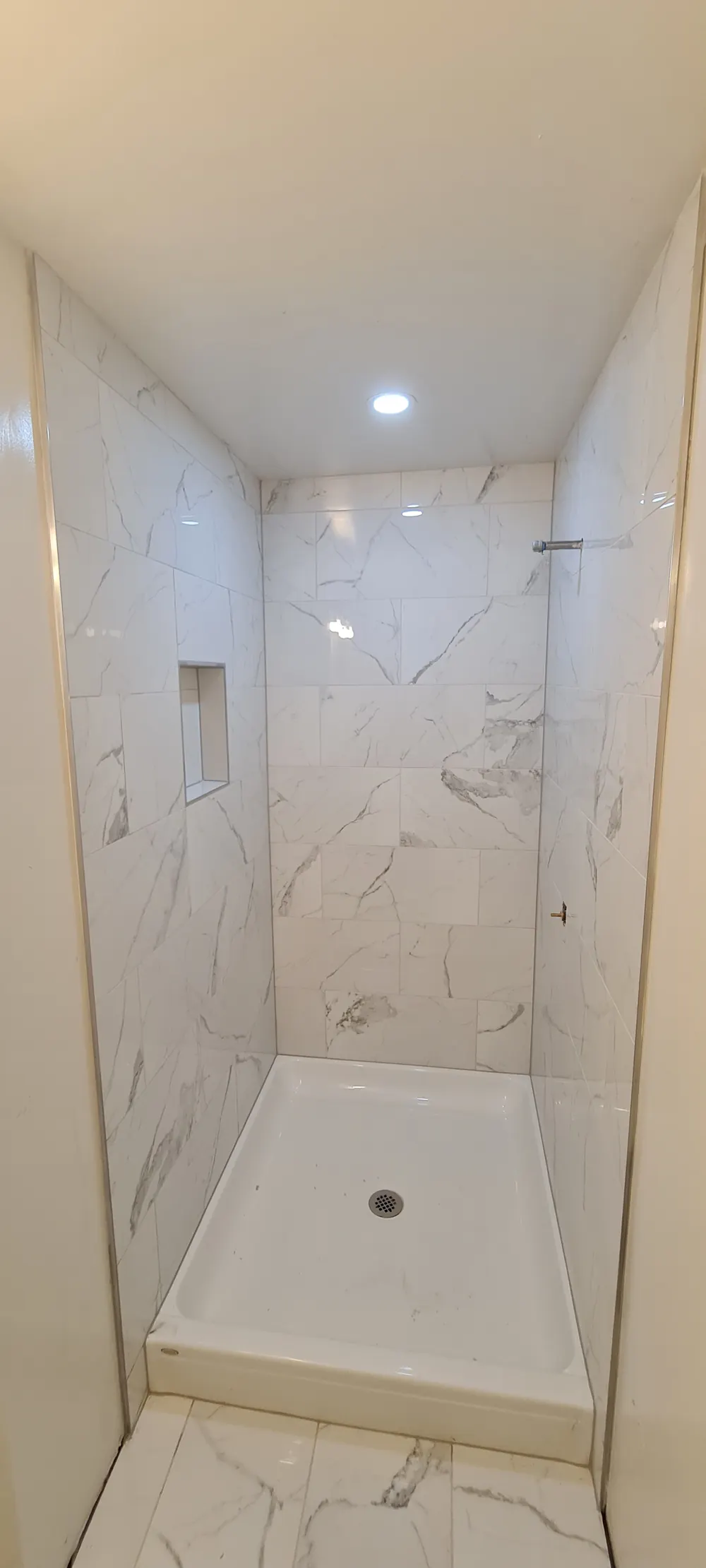 Marble-look tile shower with a corner niche