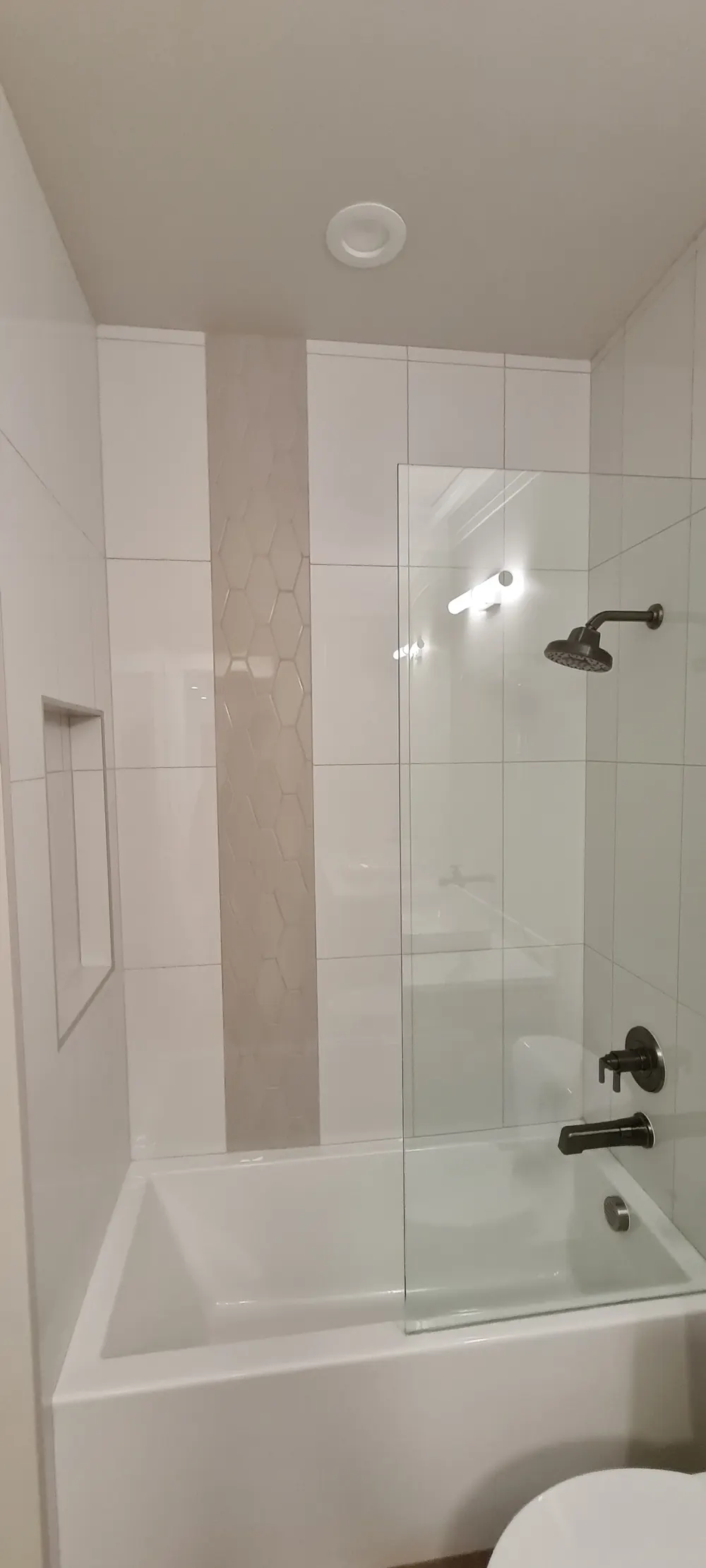 Tub with a glass panel and a vertical tile accent