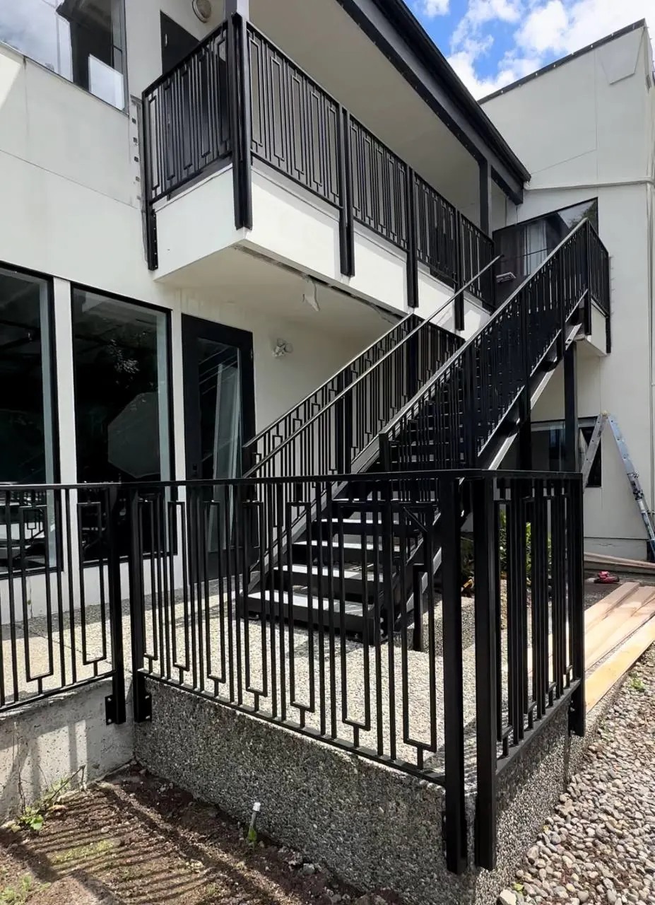 Exterior steel stair with black railings to an upper deck