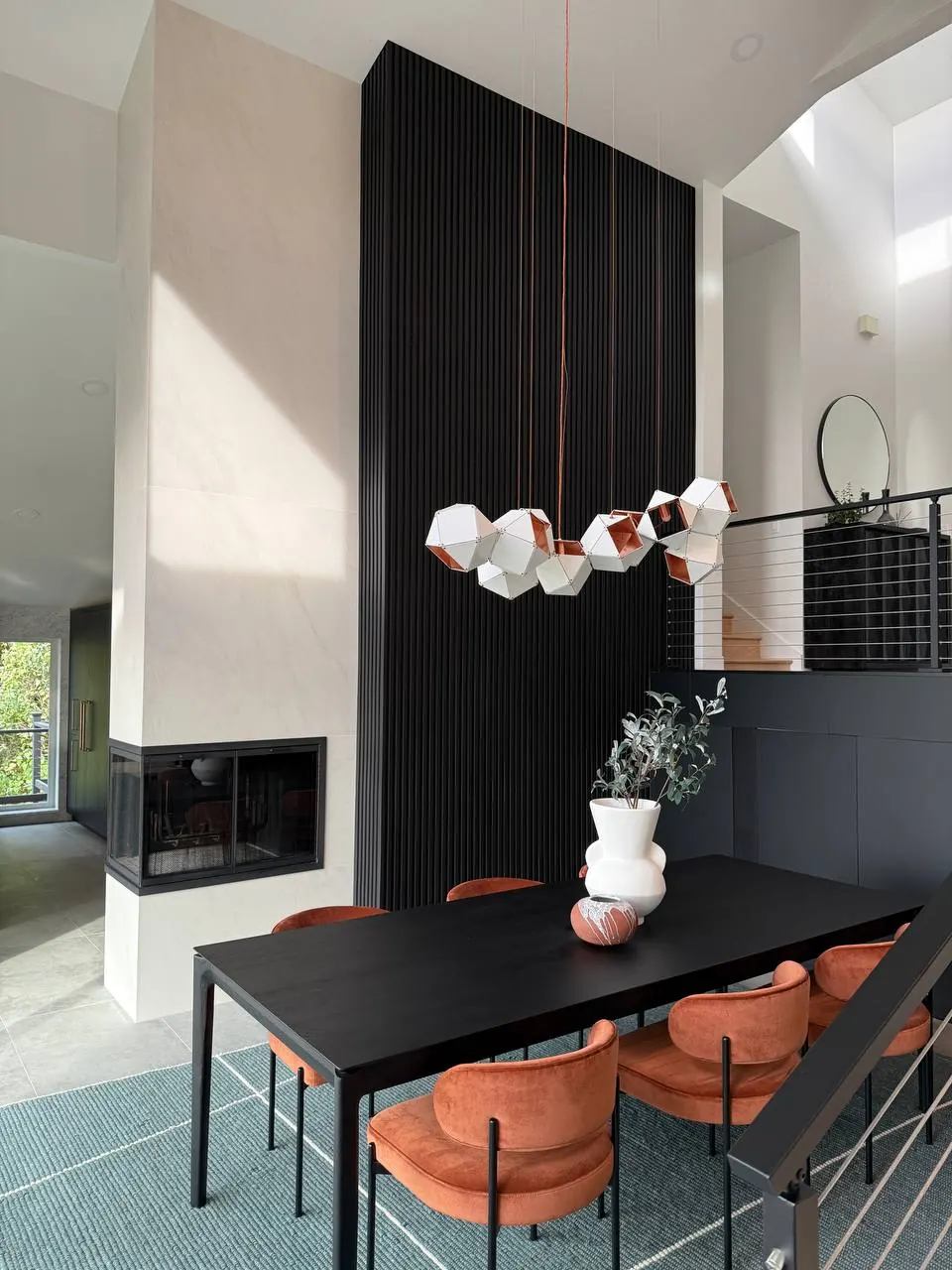 Dining area with a black fluted fireplace column and modern chandelier