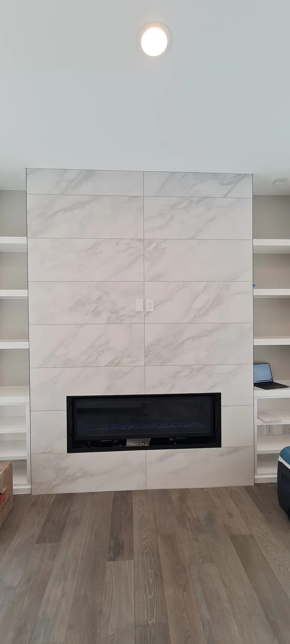 Tile fireplace wall with a linear fireplace and built-in shelves
