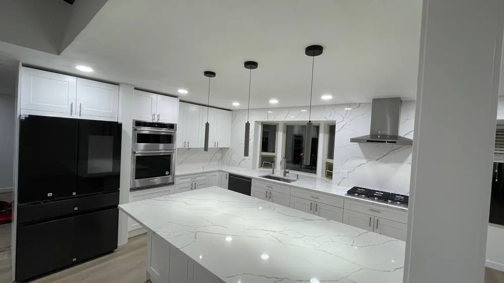 White kitchen with black appliances, a large island and pendant lights