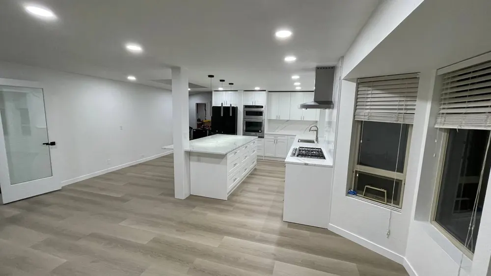 White kitchen with a large island and gray plank floor