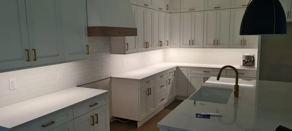 White L-shaped kitchen with a wood range hood accent