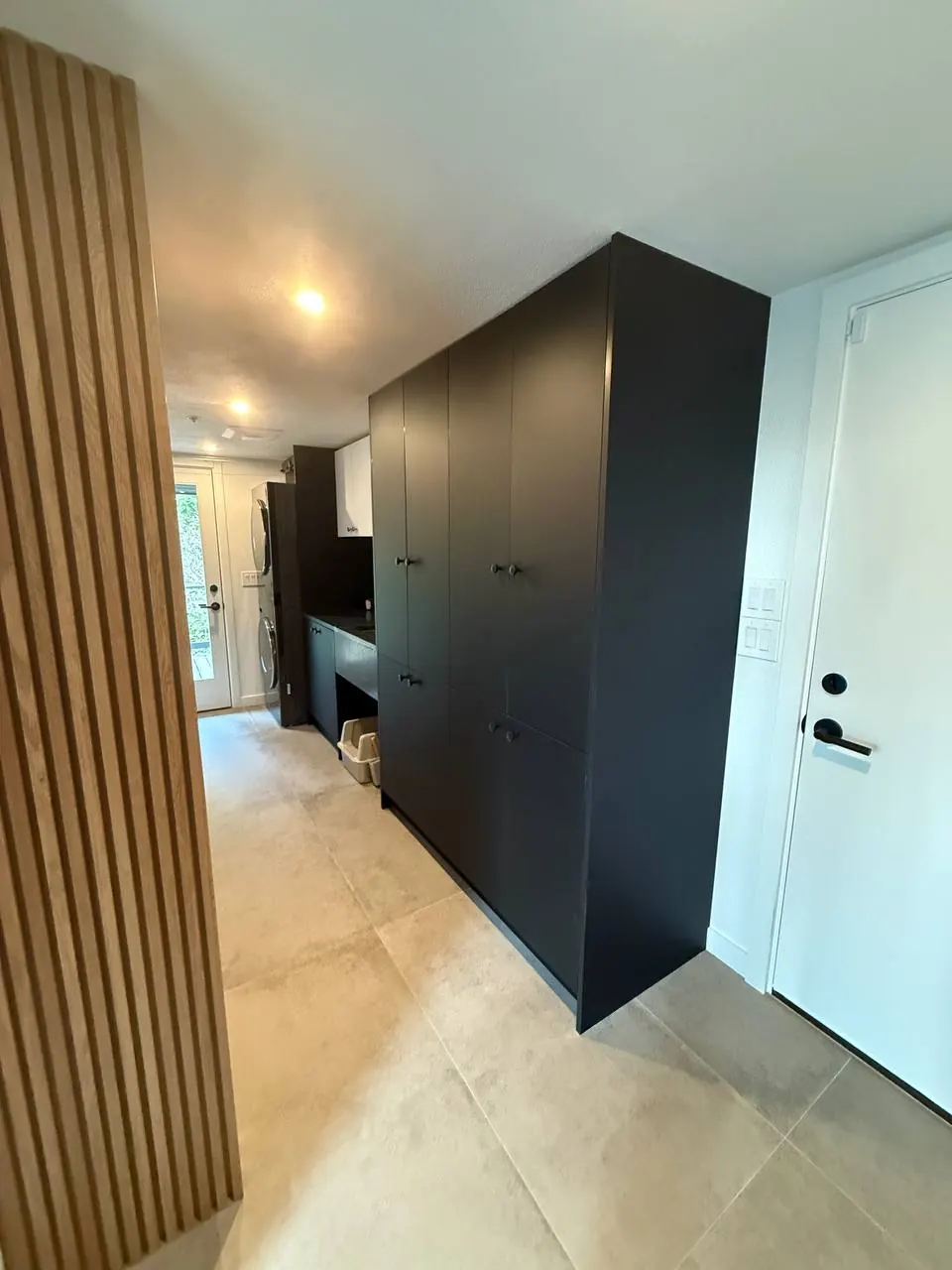 Black tall cabinets beside a wood-slat wall
