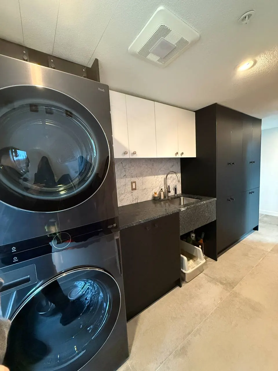 Laundry room with a stacked washer and dryer and black cabinets