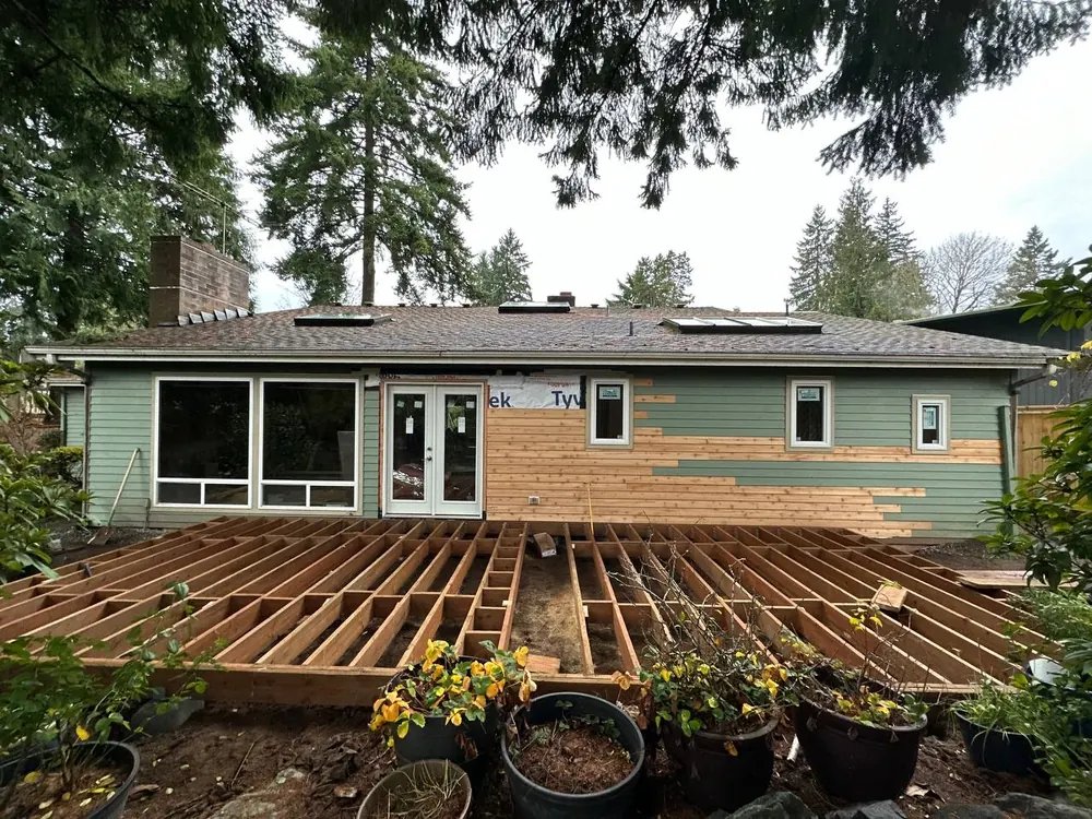 New deck framing behind a green house