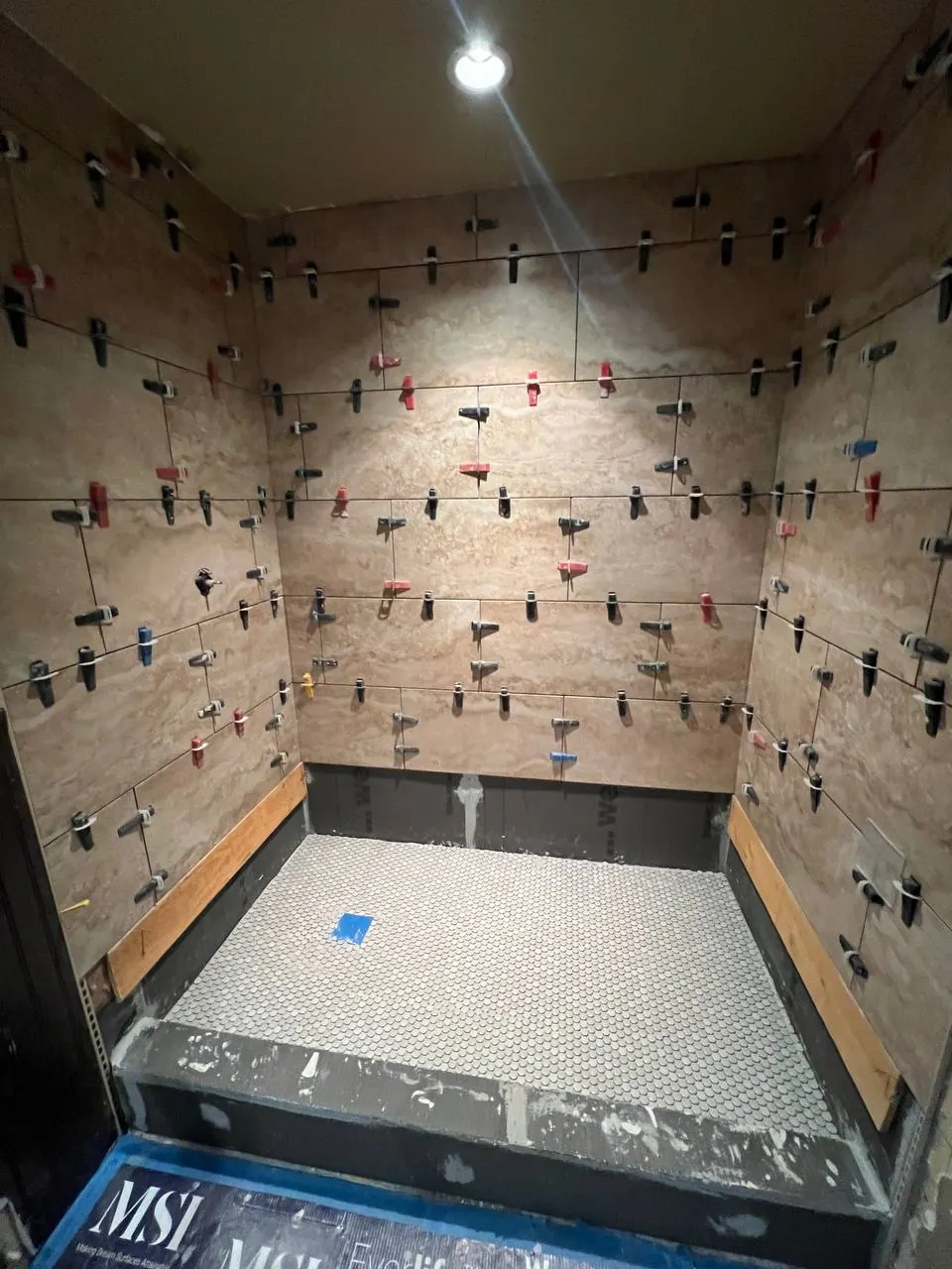 Shower walls mid-installation with tile leveling clips