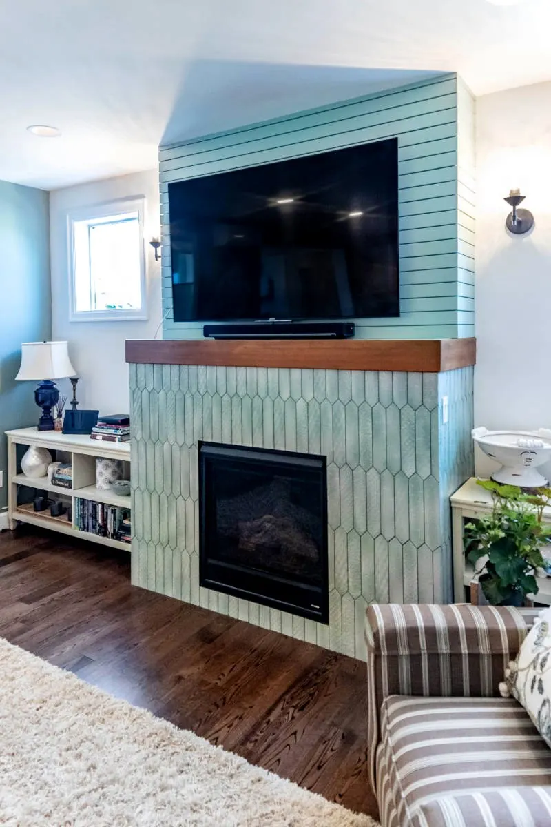Tiled fireplace with a wood mantel and mounted TV