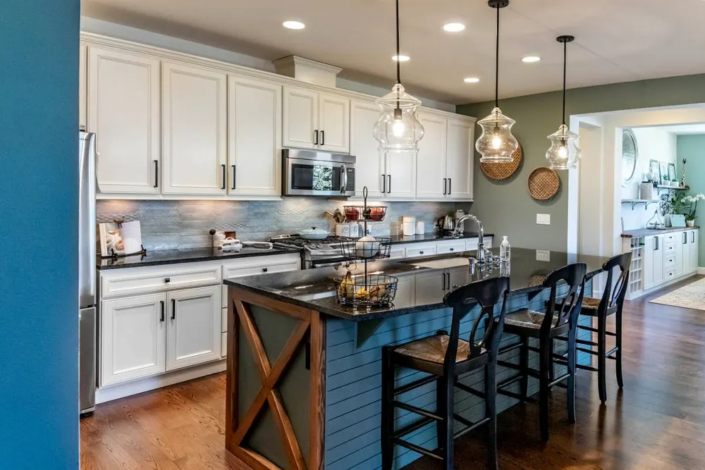 Kitchen with blue walls, white cabinets and a dark island with stools