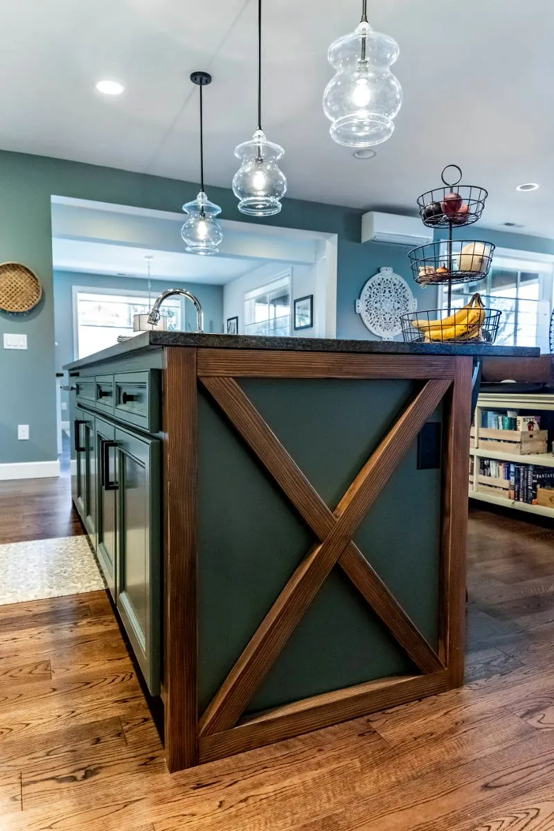 Kitchen island with dark wood X-panel ends and glass pendants