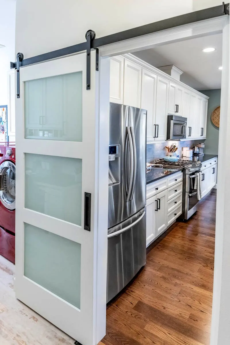 White sliding barn door opening to the kitchen