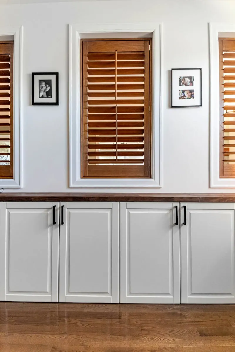 Built-in cabinetry beside a window with wood shutters