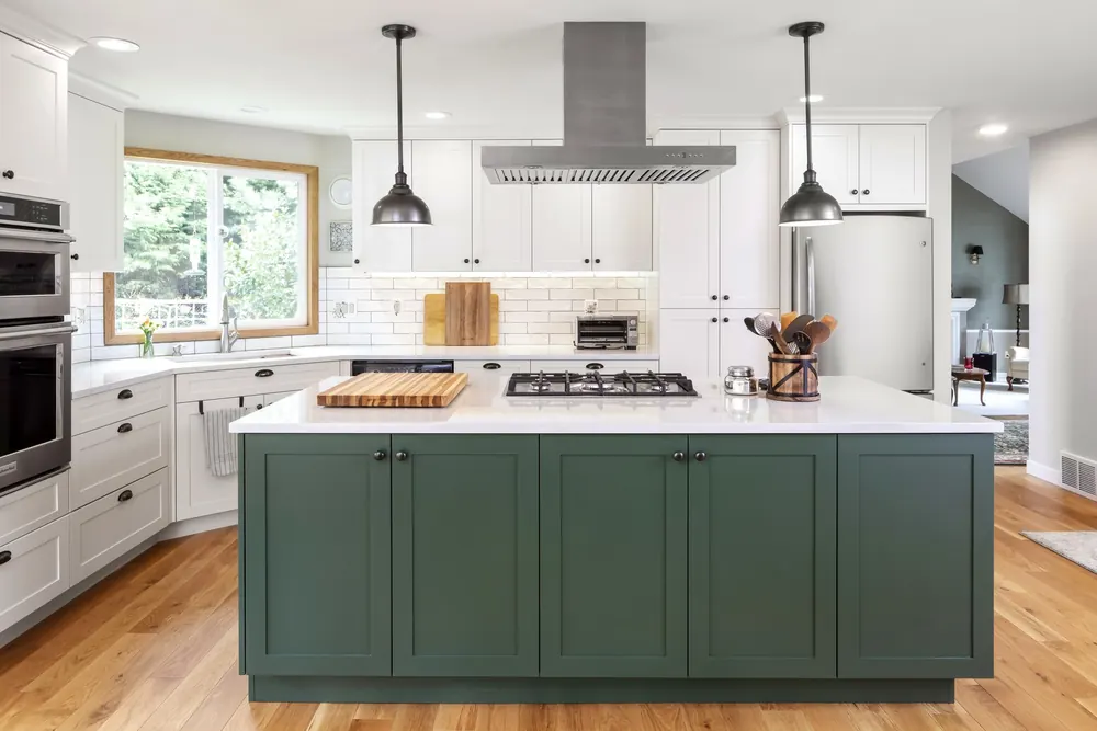 Kitchen with a green island, stainless range hood and white shaker cabinets