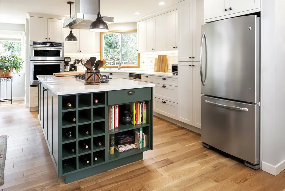 Green island with wine cubbies next to a stainless refrigerator