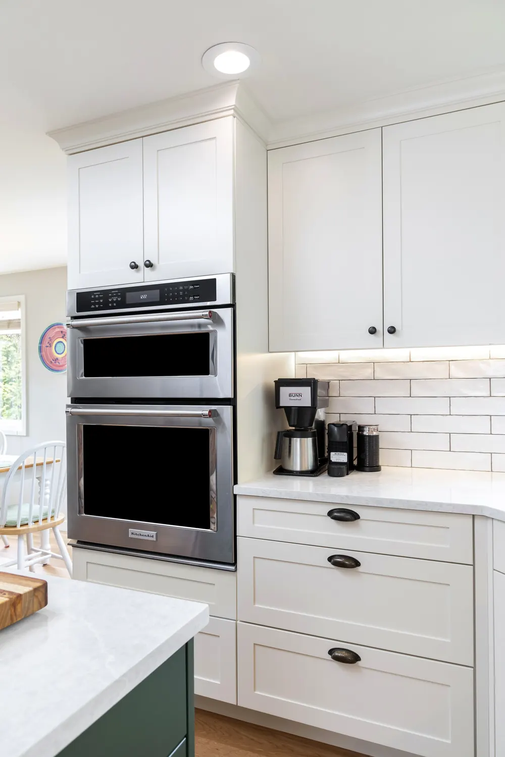 White cabinets with double wall ovens and a coffee station
