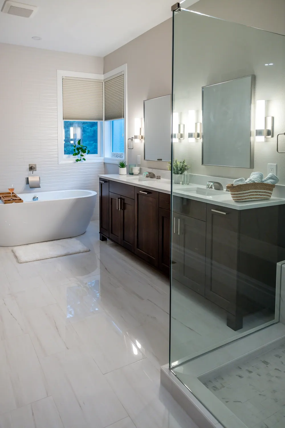 Freestanding tub between a glass shower and a dark wood vanity