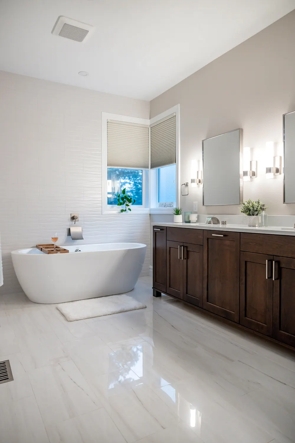 Primary bath with a white tile floor, freestanding tub and double vanity