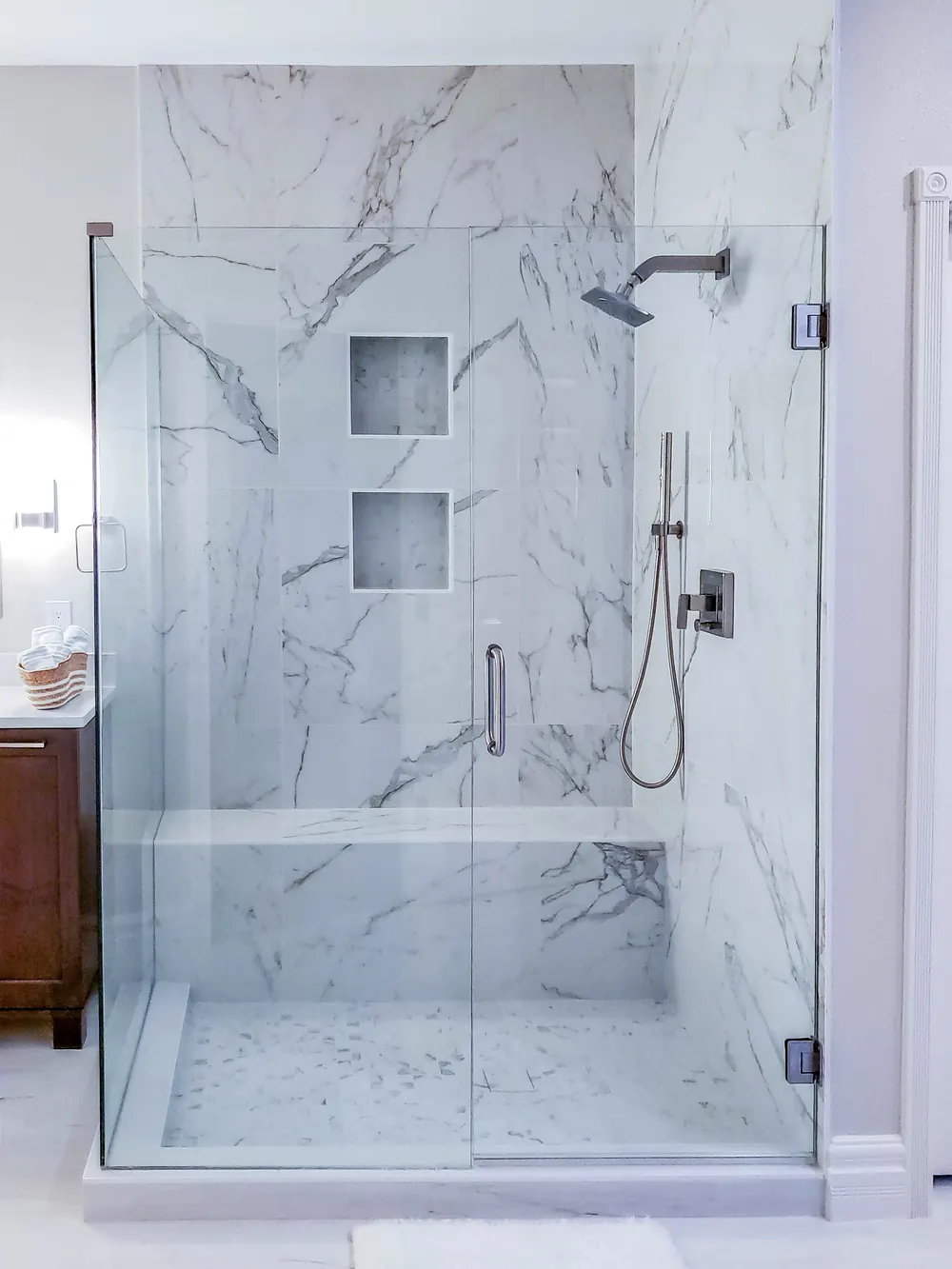 Glass shower with marble-look wall tile and two niches