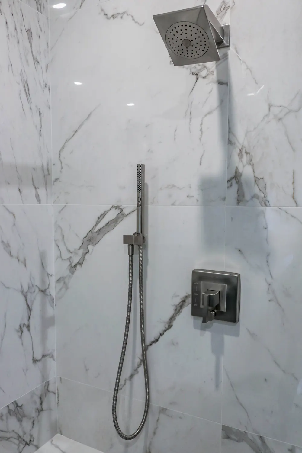 Shower valve and handheld shower on marble-look tile