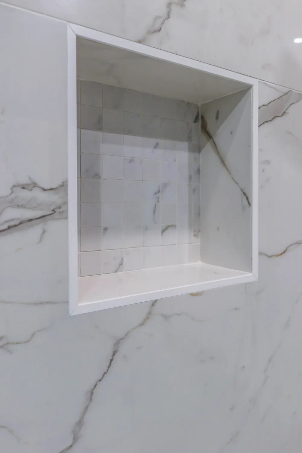Recessed shower niche in marble-look tile