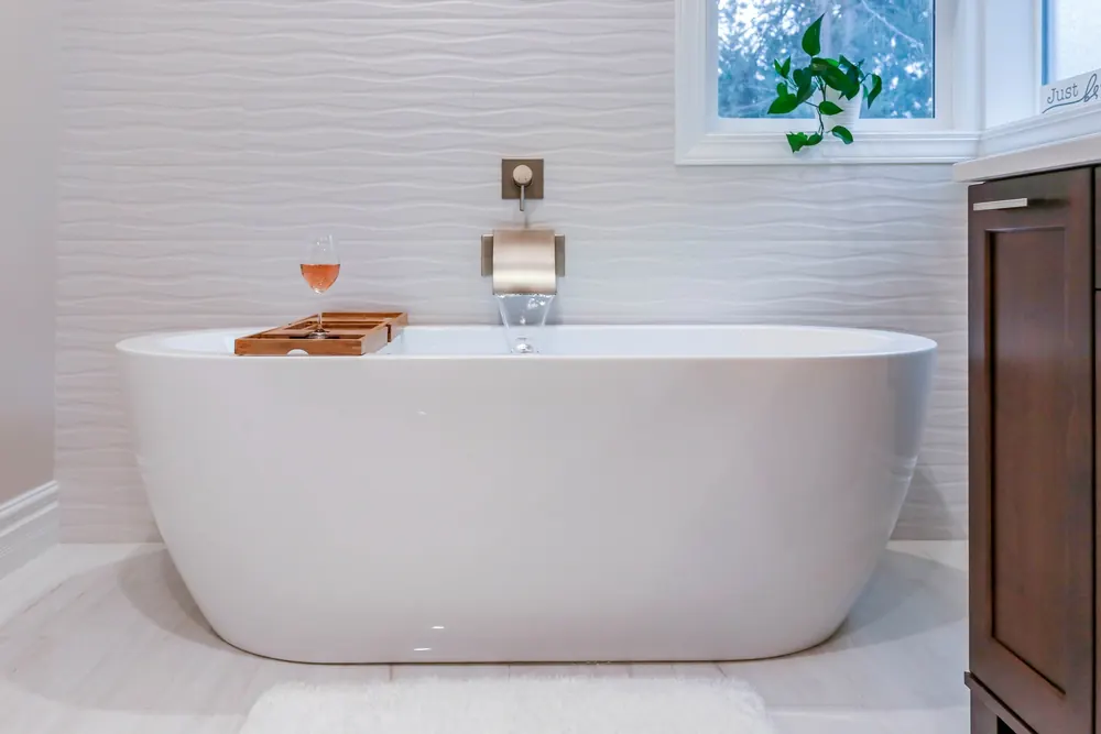 Freestanding tub against a textured white tile wall