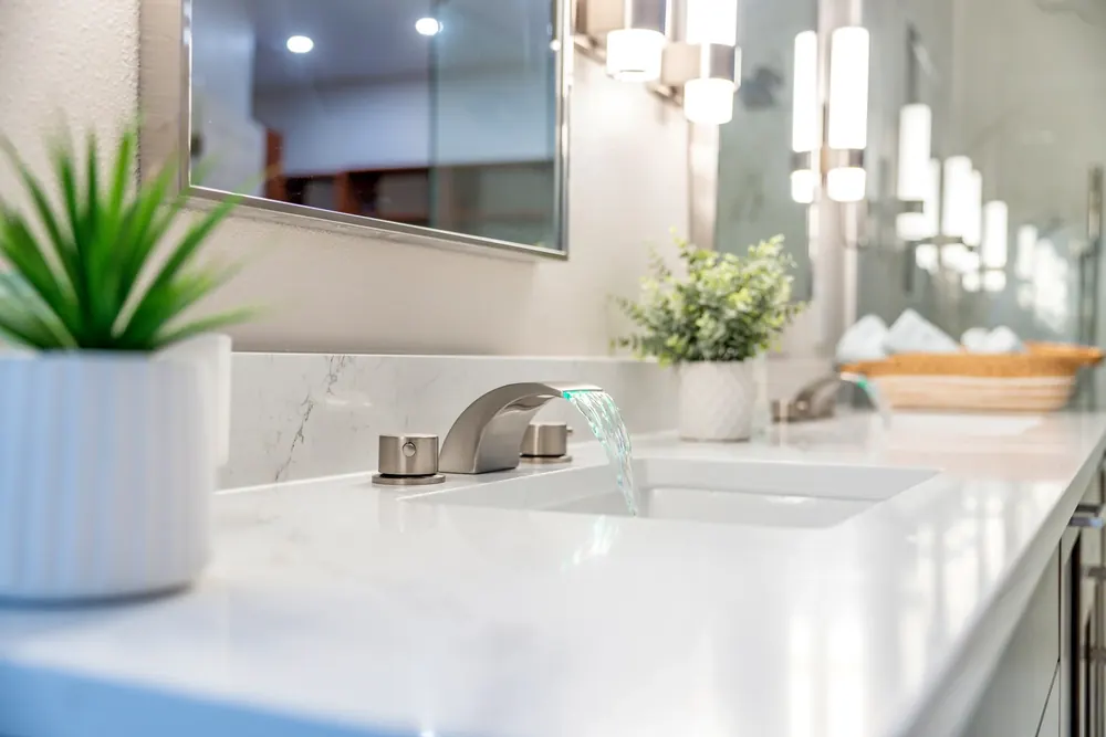 Double vanity with white counters and wall sconces