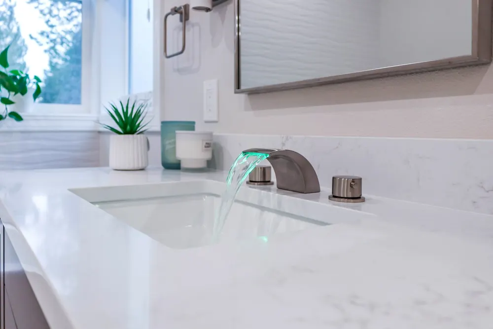 Vanity sink with a bronze faucet and a window view