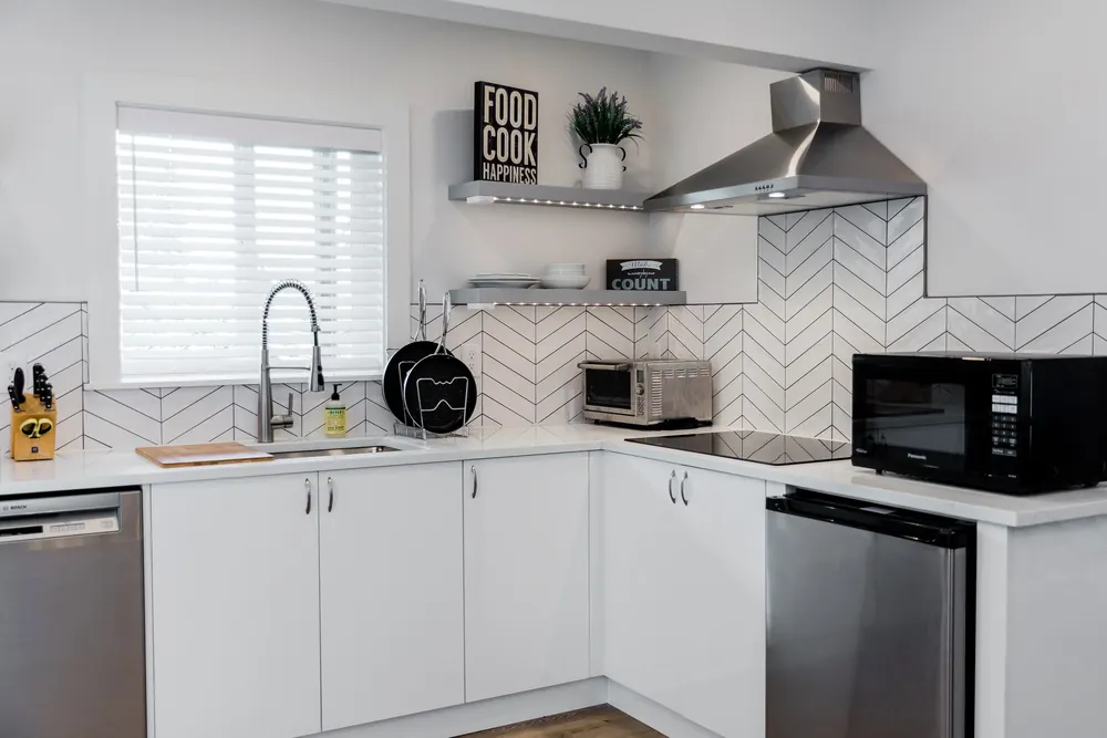 Small white kitchen with open shelving and stainless appliances