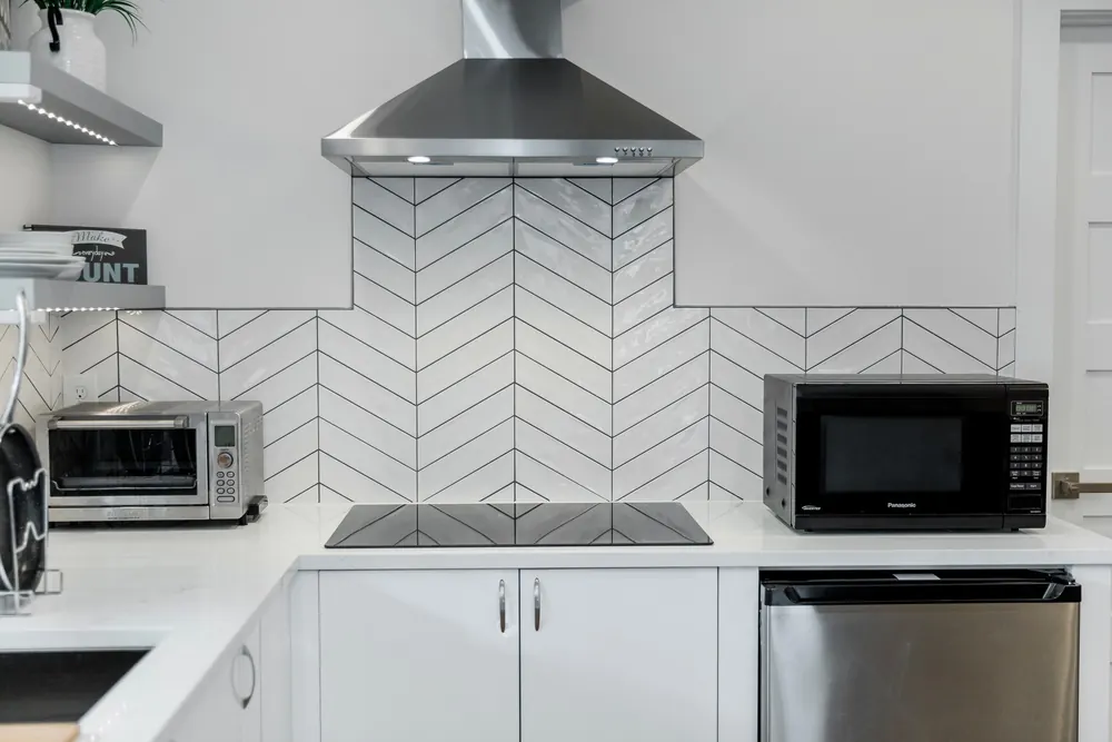 Herringbone tile backsplash under a stainless range hood