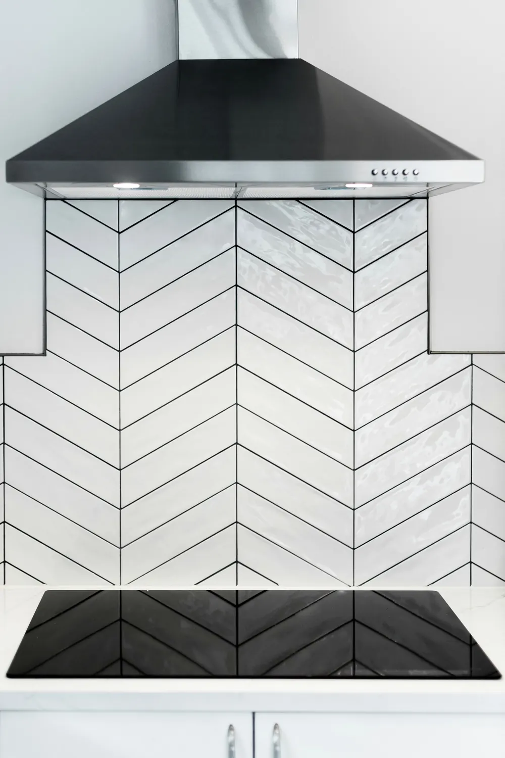 Range wall with a black hood and white herringbone tile