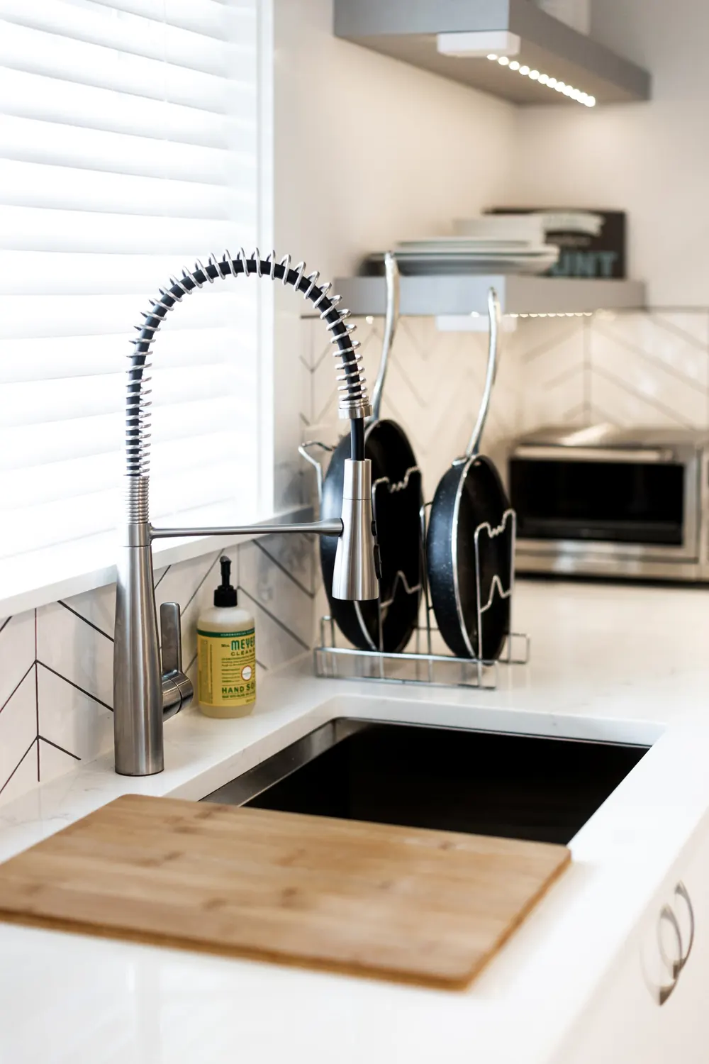 Kitchen sink with a pull-down faucet and wood cutting board